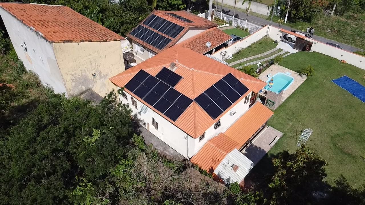 Casa com telhado de telhas laranja, piscina e painéis solares instalados em duas águas do telhado