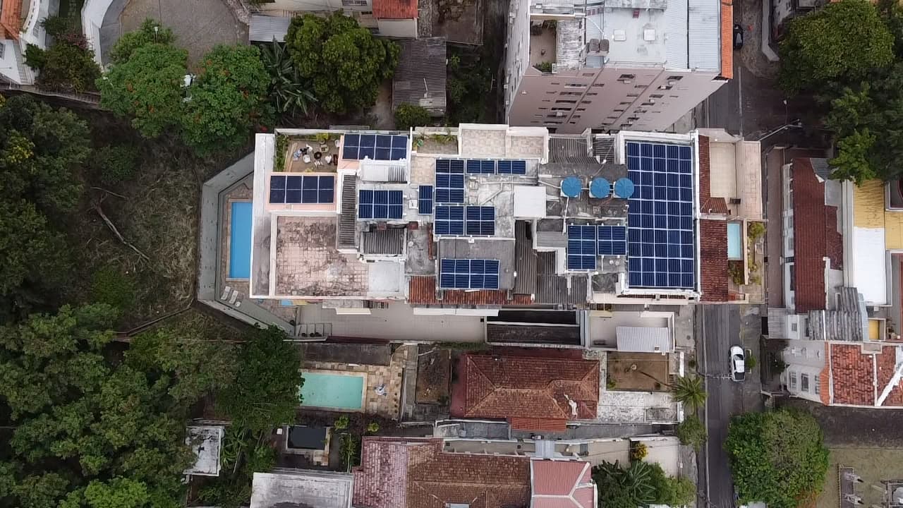 Vista aérea de prédio urbano com piscina na cobertura e painéis solares instalados junto à área de lazer