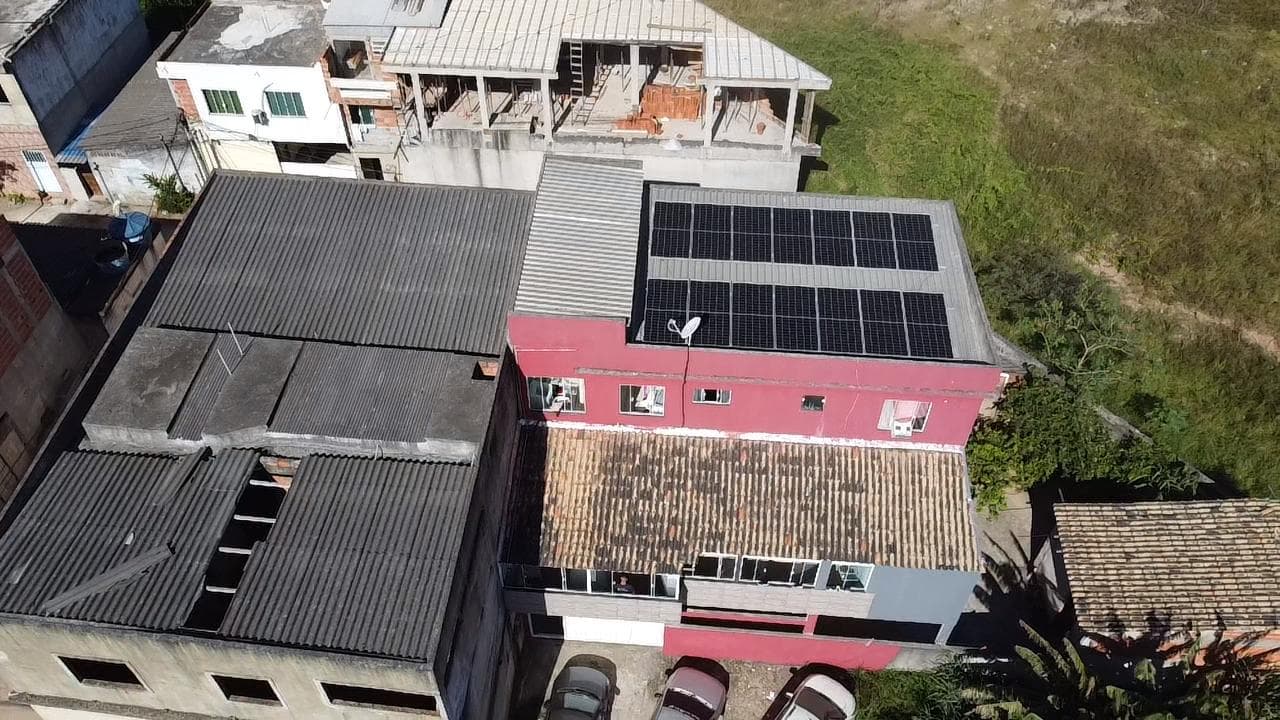 Vista aérea de prédio residencial em construção ao lado de outro com painéis solares já instalados