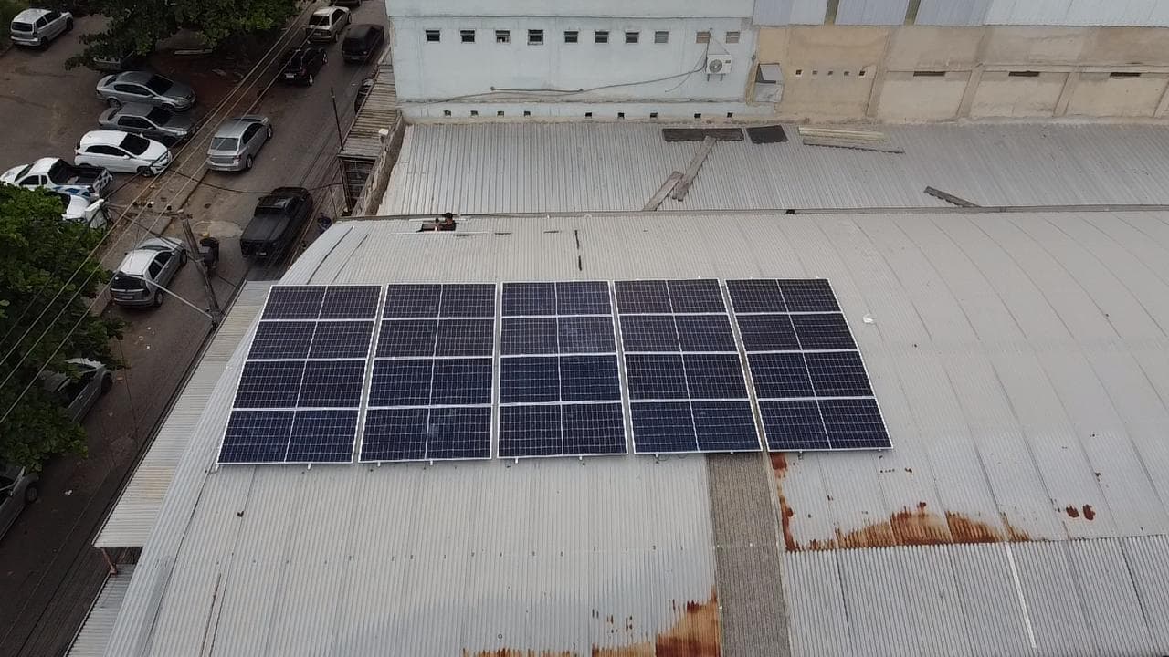 Vista aérea de painéis solares num telhado metálico de galpão comercial