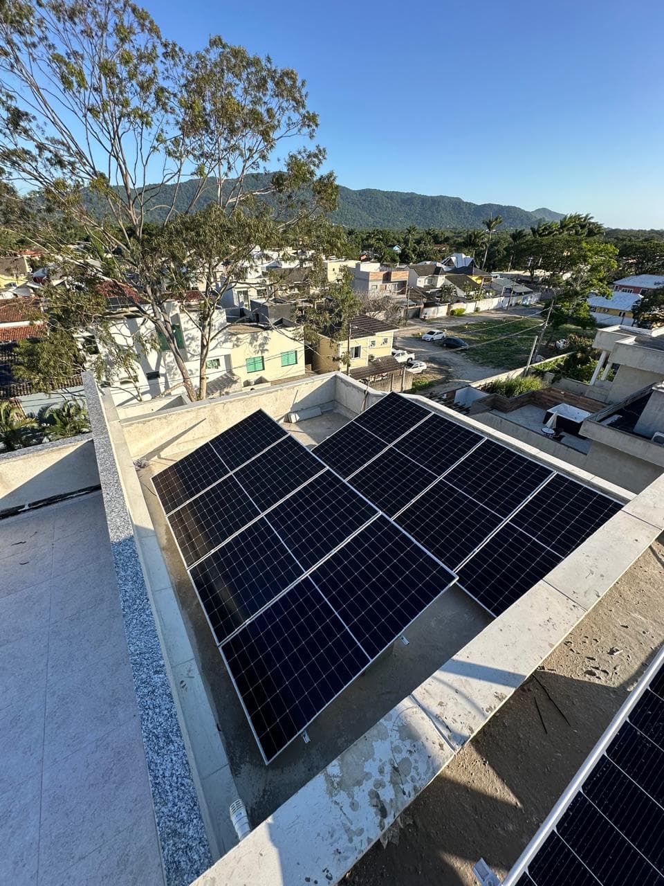Painéis solares recém-instalados em telhado, com vista para montanhas ao fundo
