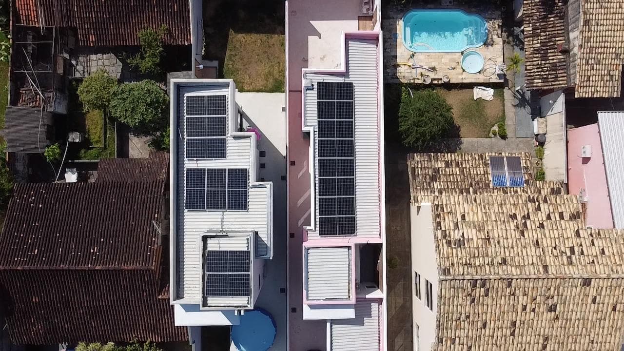 Vista aérea de casas geminadas com painéis solares no telhado e piscina em uma delas